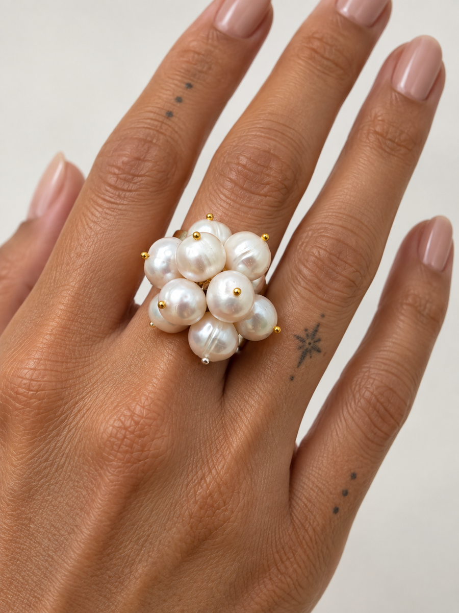 White freshwater pearl cluster ring worn on a hand, showcasing its rounded pearl arrangement and sterling silver band.
