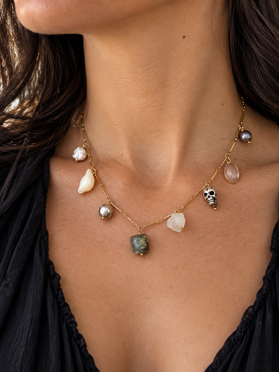 1. Artifact charm necklace featuring layered pearl, pyrite, and gemstone charms on a gold-filled chain, worn close to the neckline