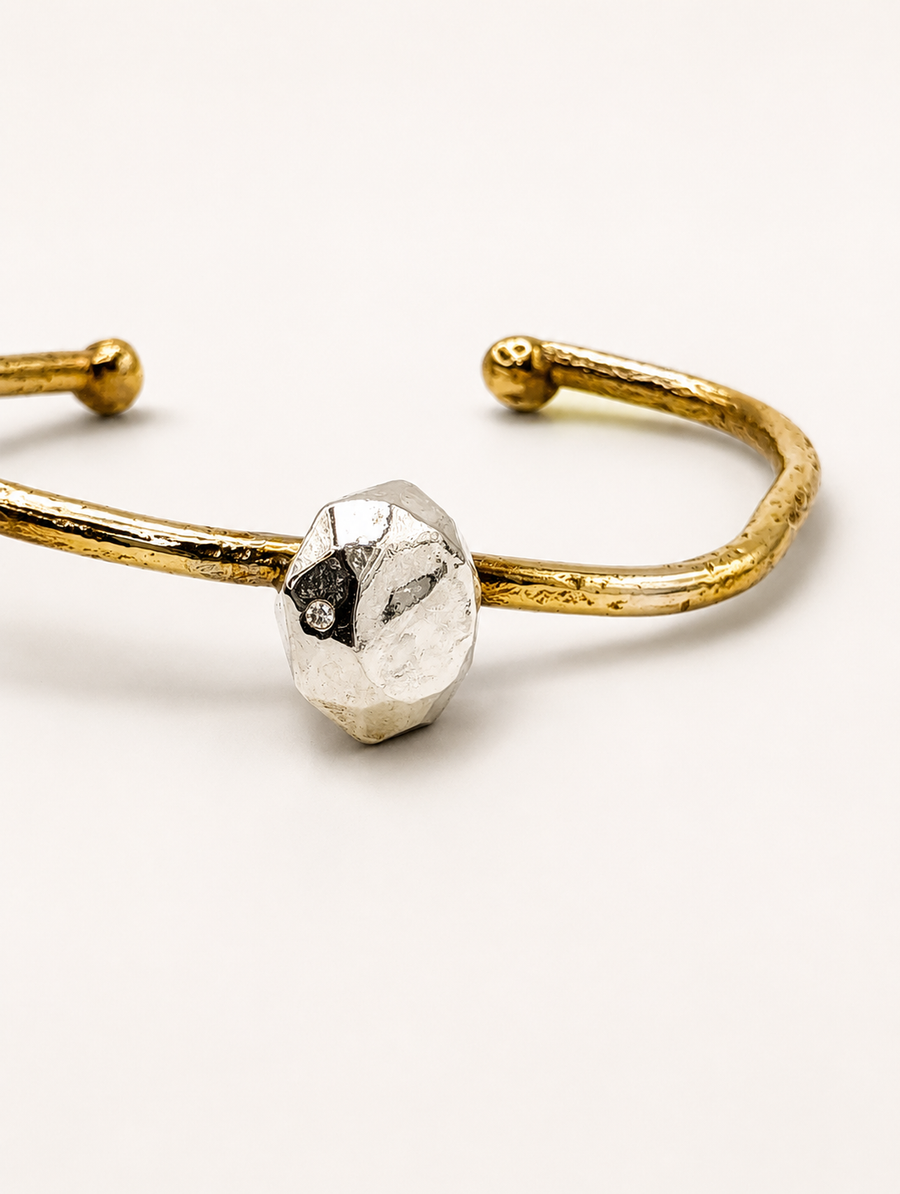 Silver cuff bracelet with a round diamond detail photographed from the side